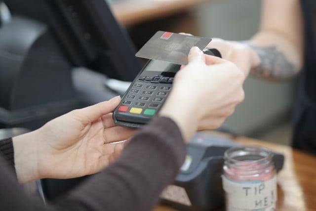 Customer handing a payment card to an employee for a POS purchase 