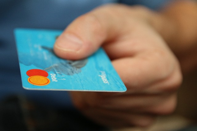 Person's hand holding out a payment card