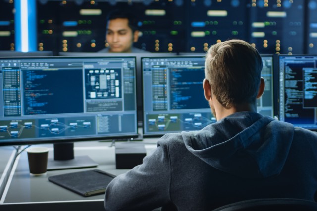 Man reviewing multiple screens with detailed data