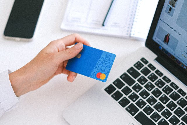 Person holding a payment card to make an online purchase on a laptop